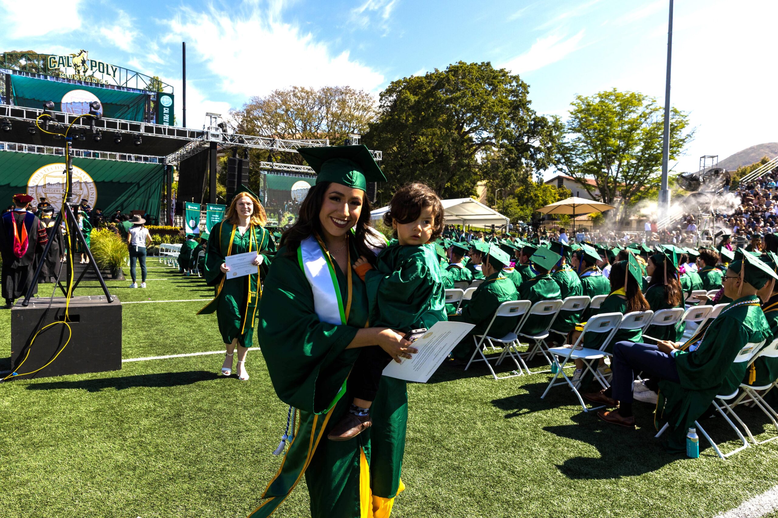 A graduating student walks the aisle with a small child