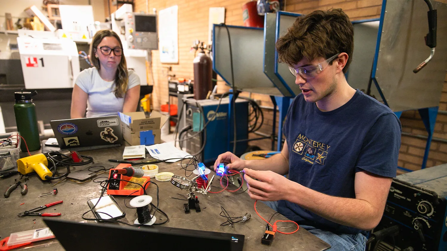 Two students work on a project that involves wires in a lab
