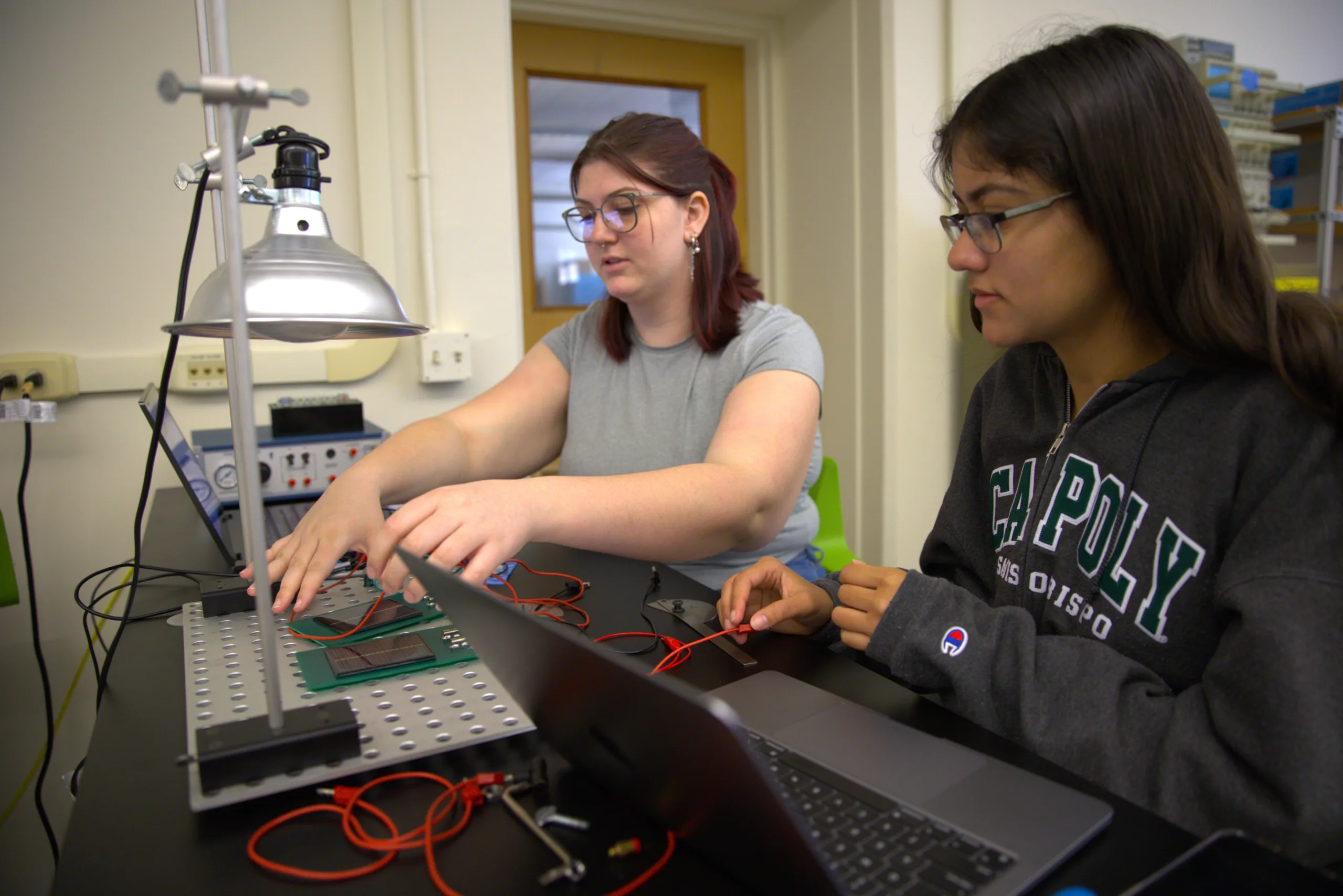 Two students work with laptops on a wiring project