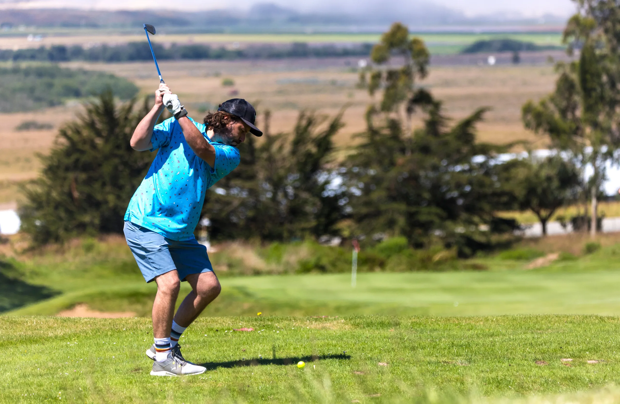 A golfer drives toward a par three hole