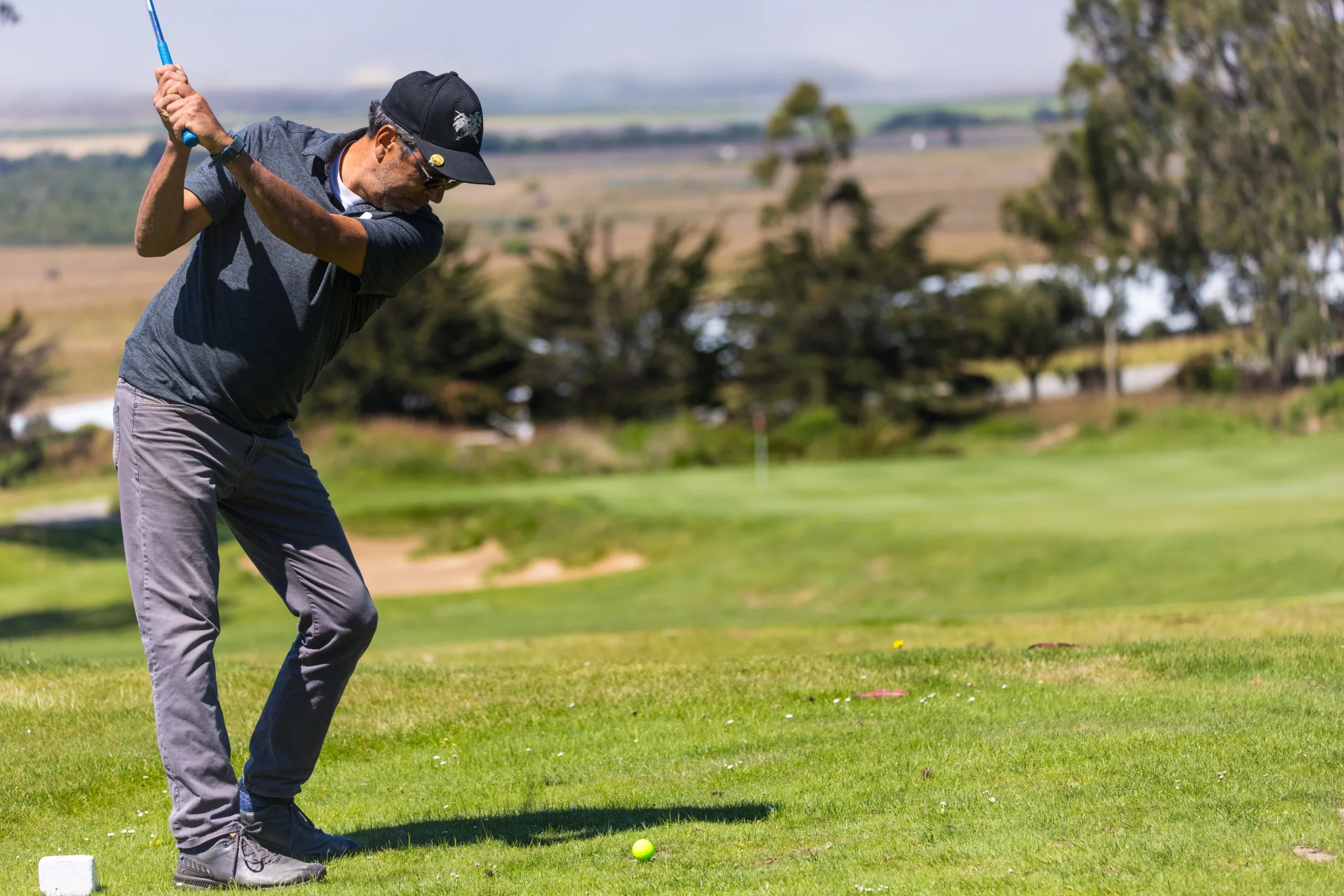 A golfer drives toward a short hole