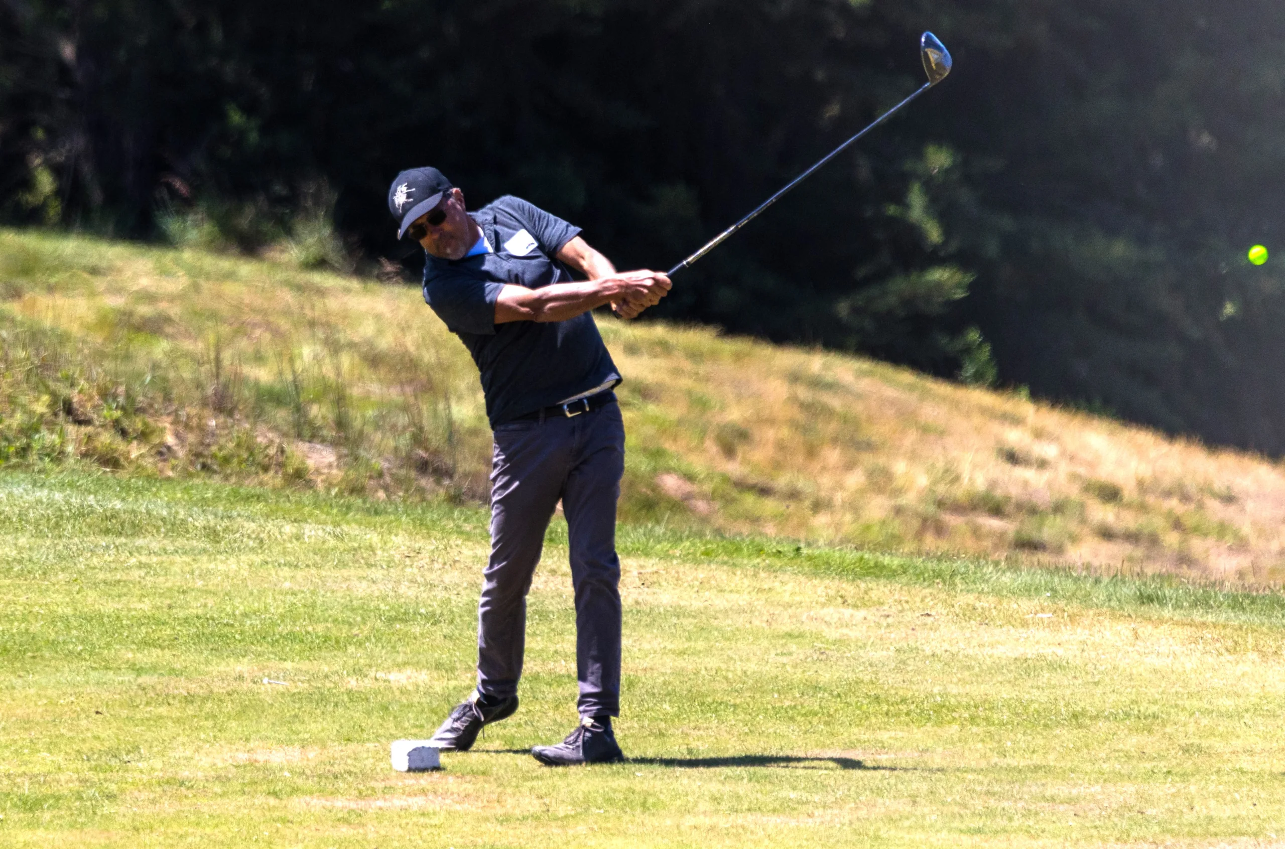 A golfer hits the ball from the fairway