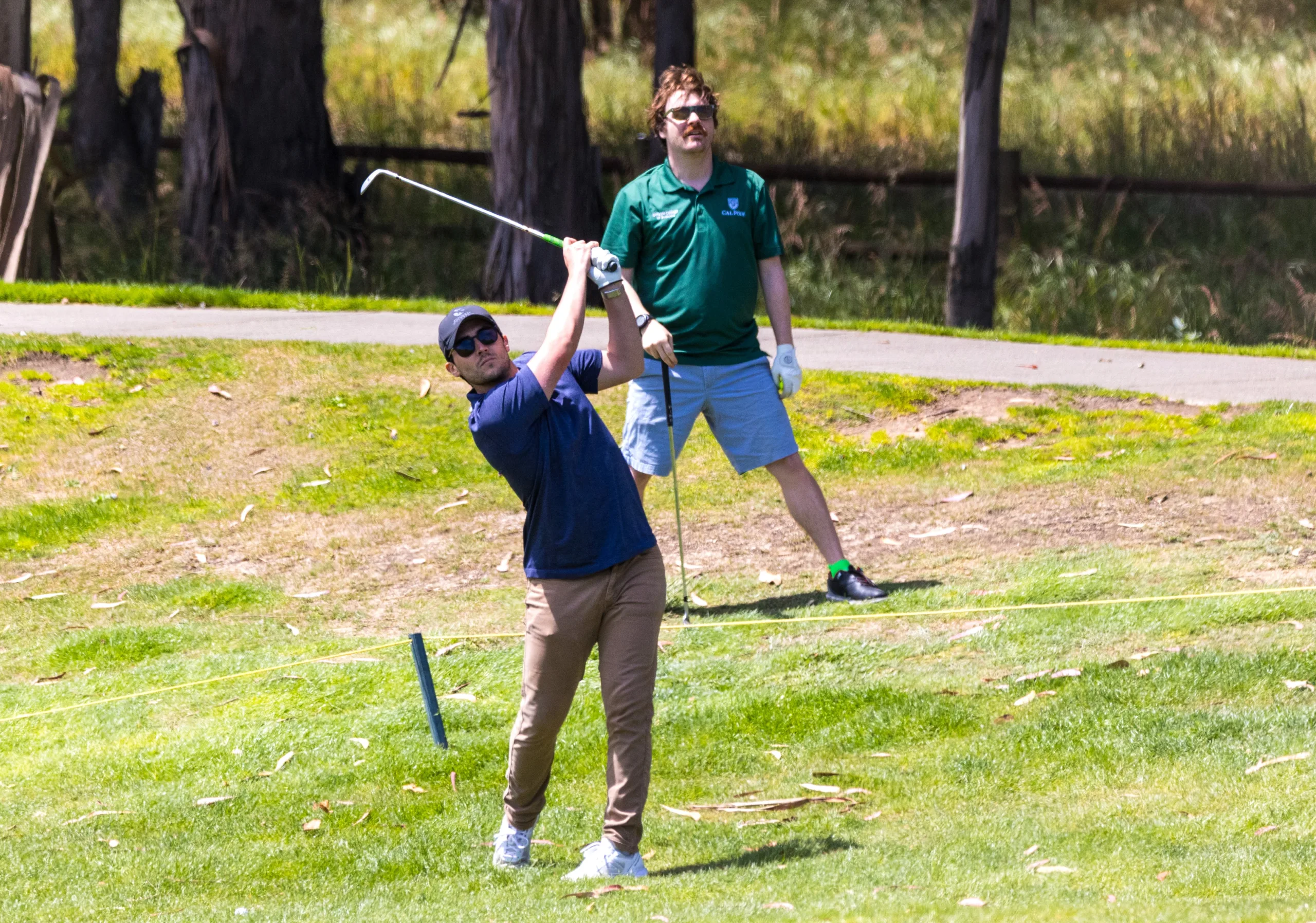 A golfer swings with an iron