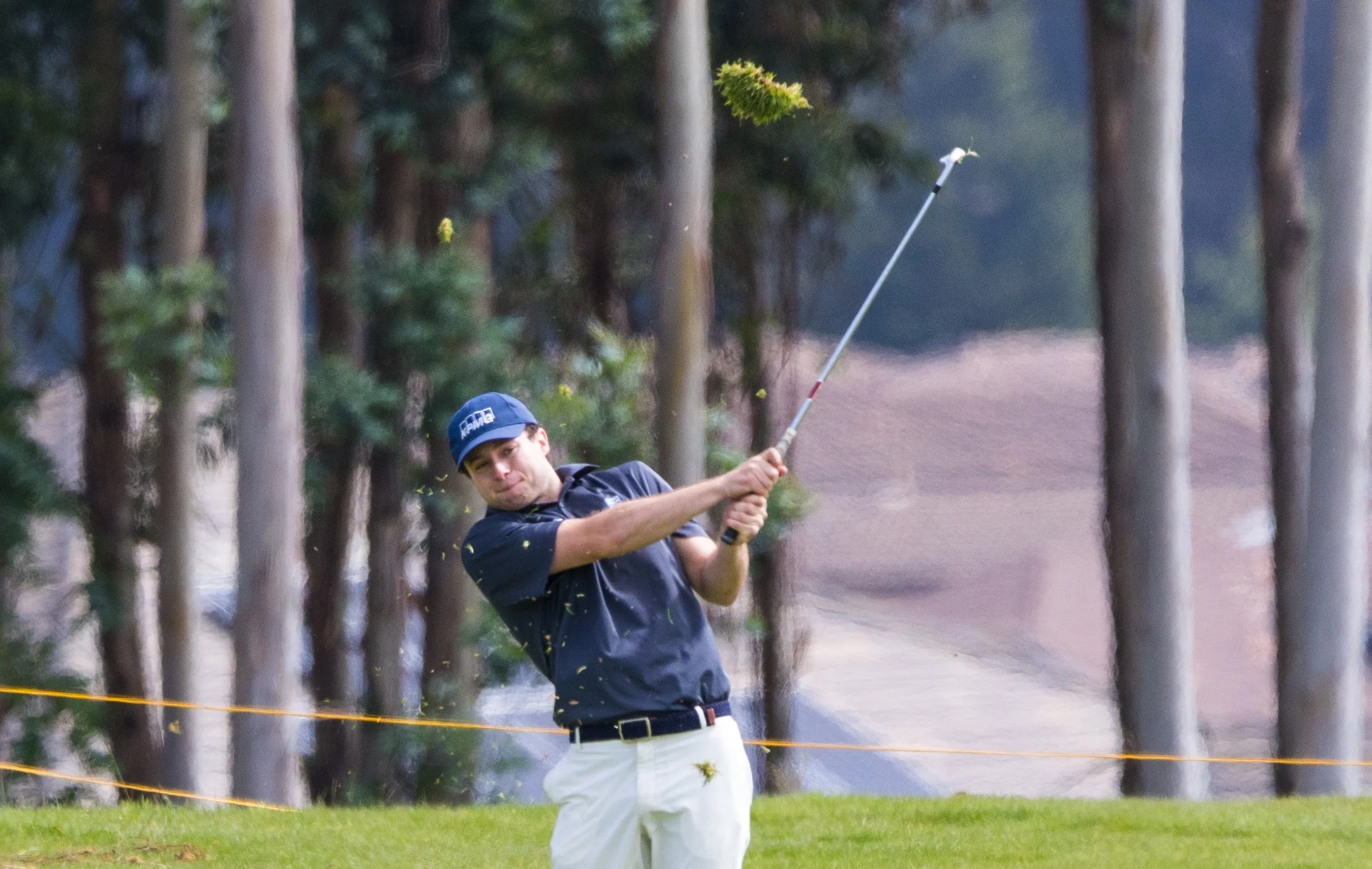 A golfer hits a ball toward the green