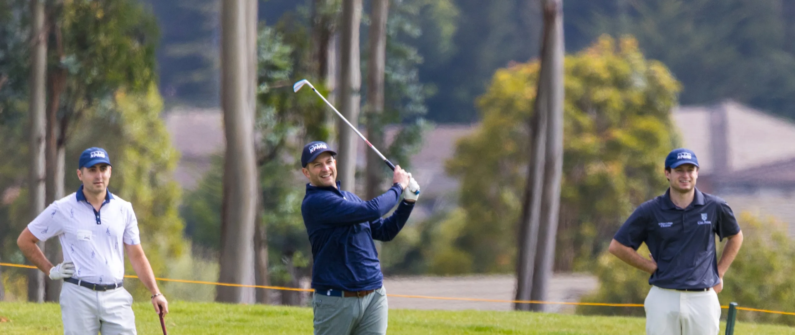 Friends watch as a golfer hits a ball