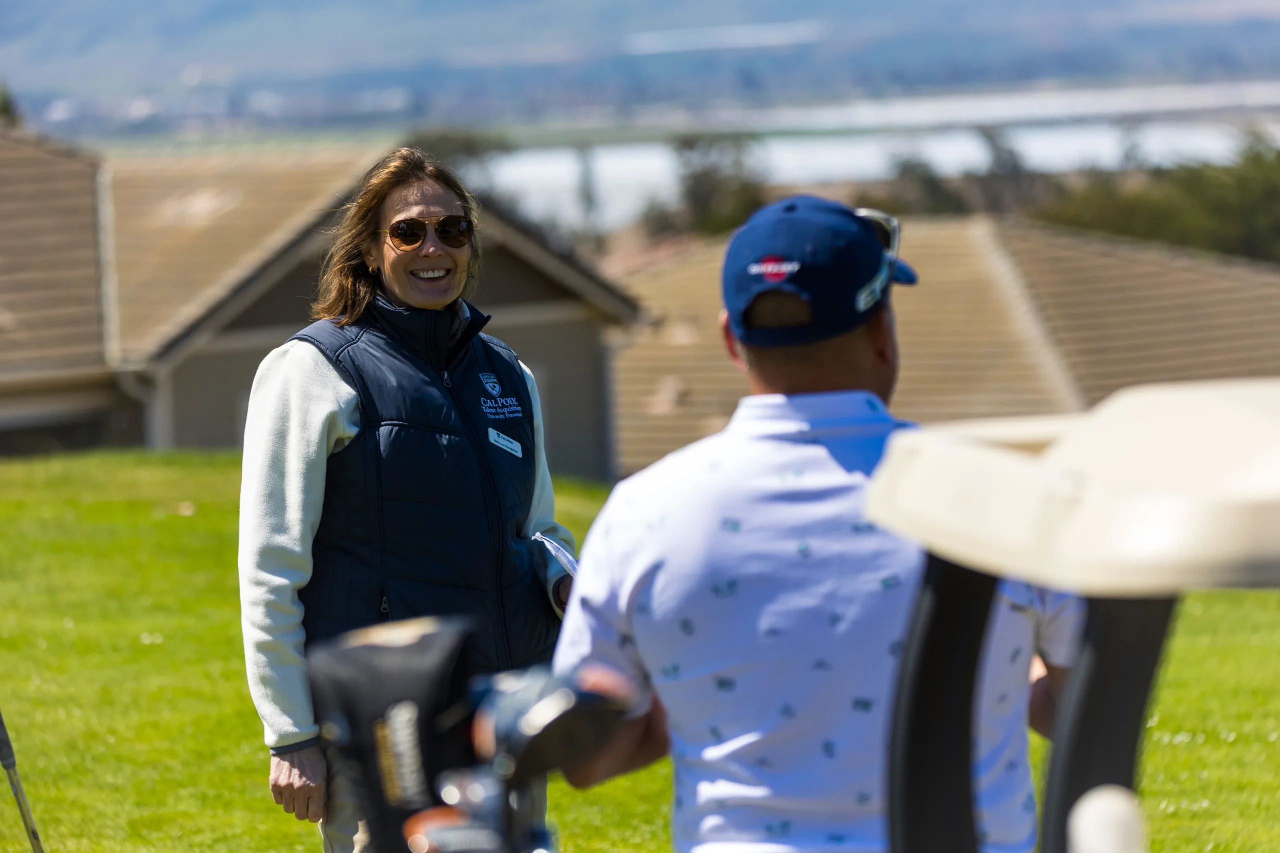 A volunteer at a golf tournament speaks to golfers