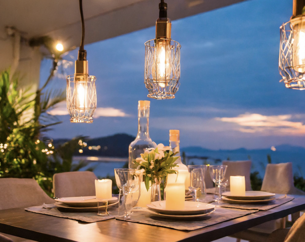 Artistic light fixtures light up an outdoor dinner table