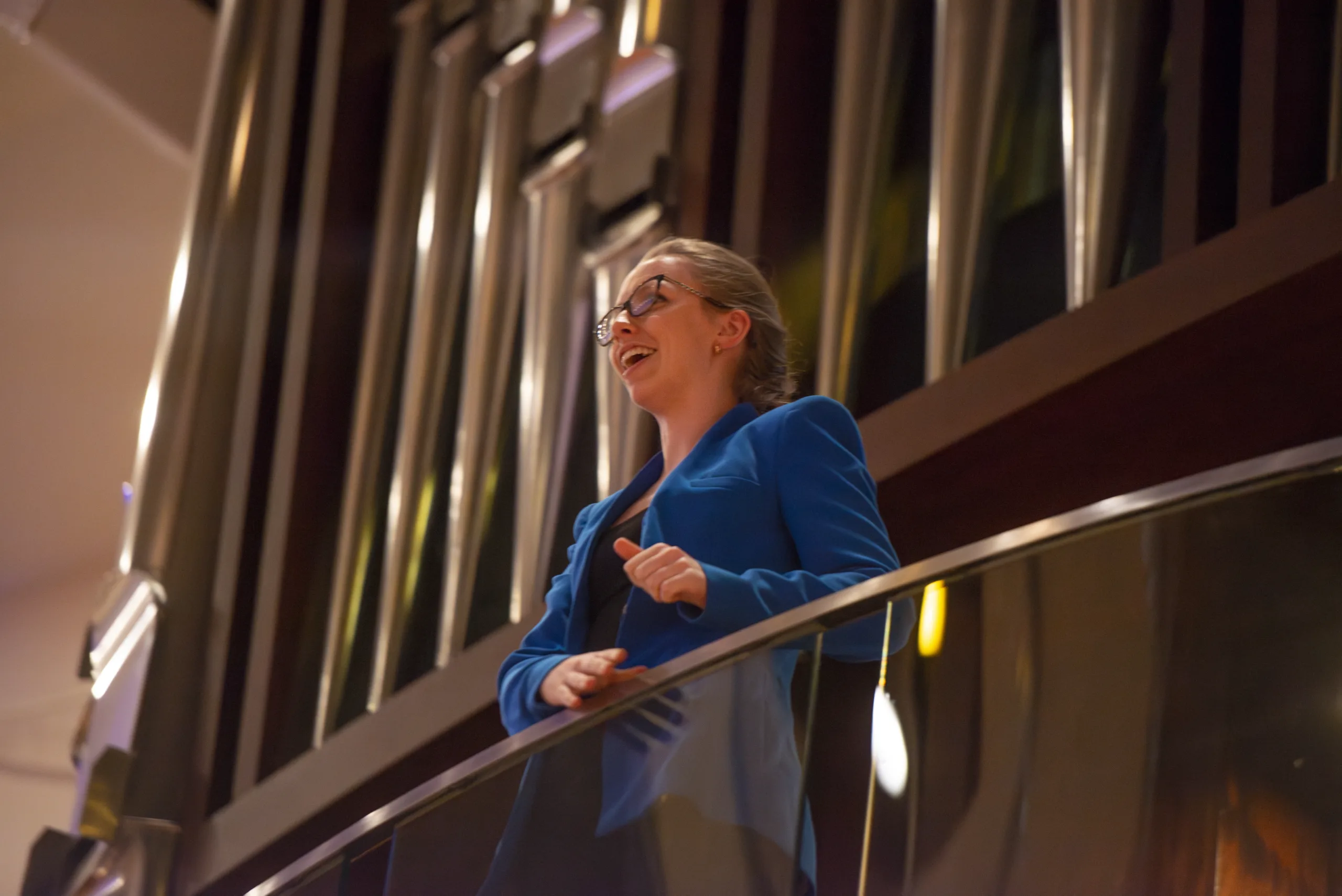 An organist speaks to students while standing in front of a pipe organ.