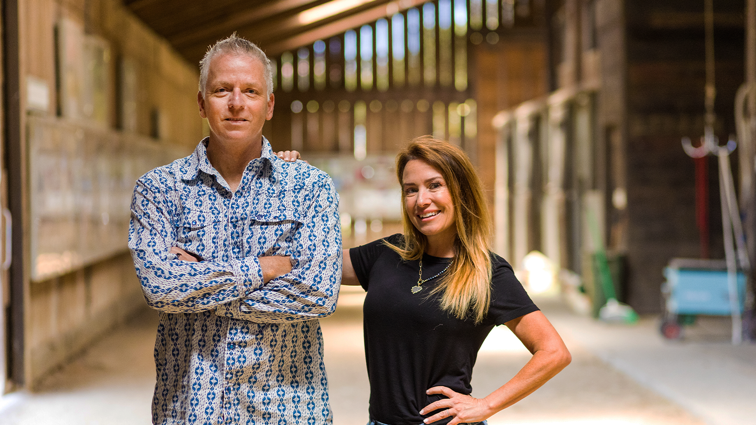 Simon and Caprice Arkell pose for a portrait inside a horse barn