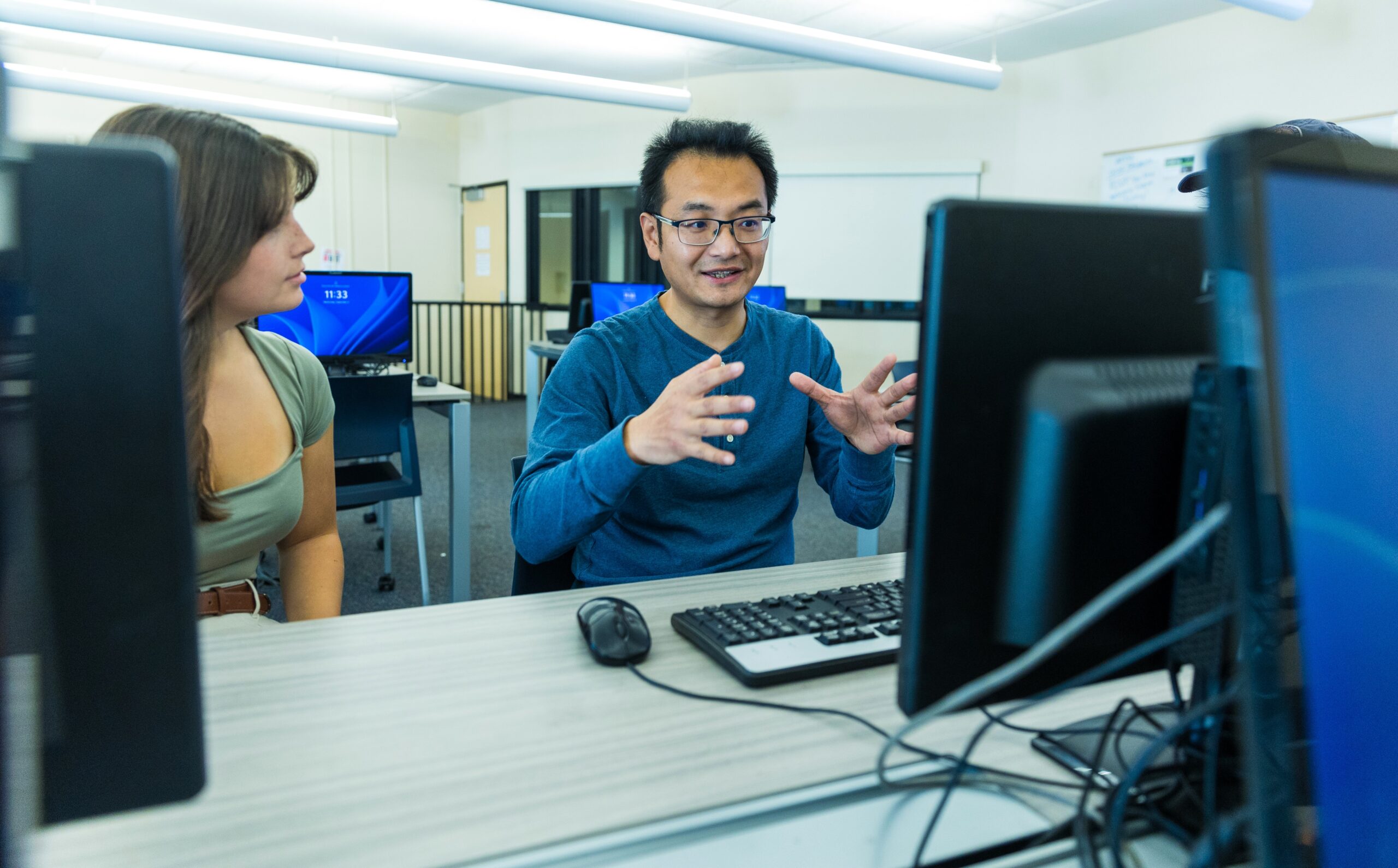 An accounting professor speaks with a student in a classroom