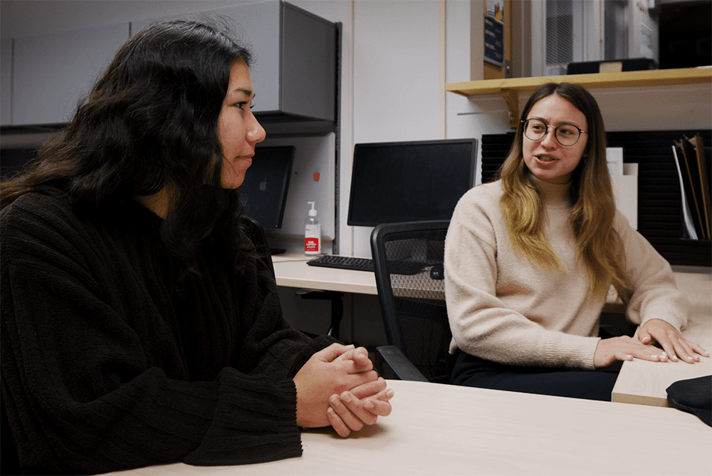 Two students in conversation at a desk