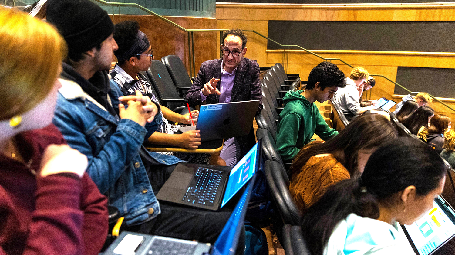 A professor speaks to a group of students in a classroom