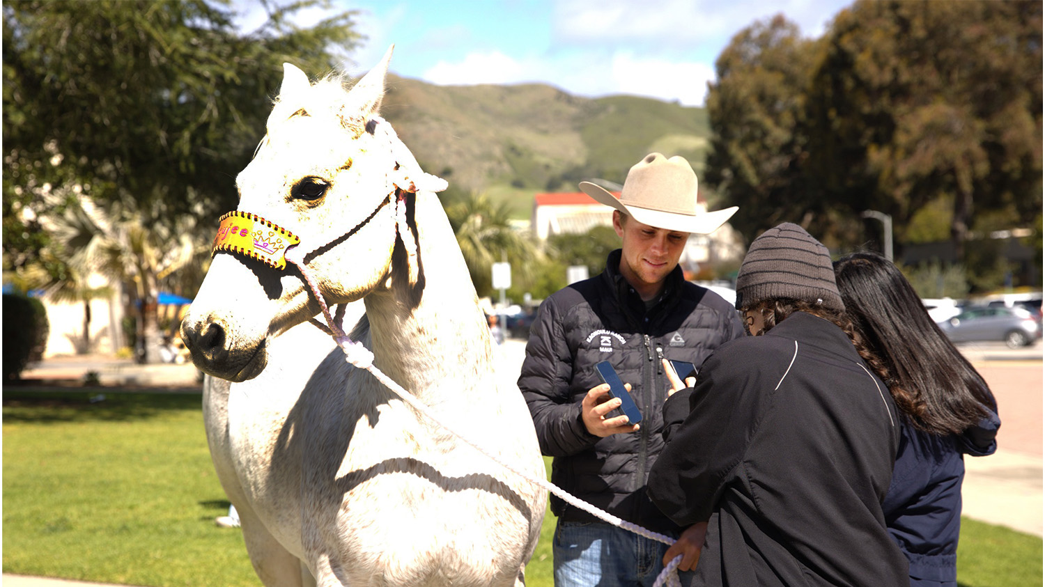 A rodeo athlete talks with students as he stands next to his horse