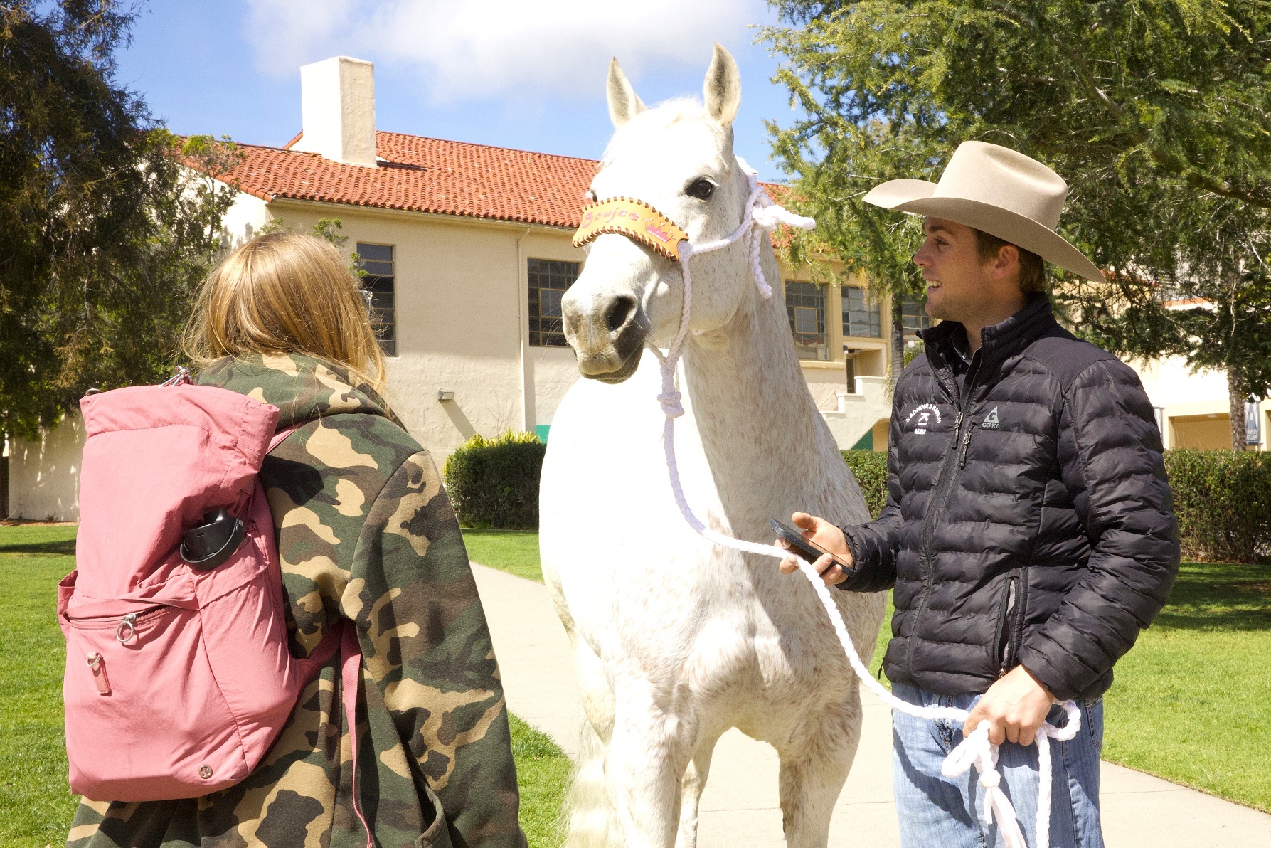 A rodeo athlete shows off his horse to a student on campus