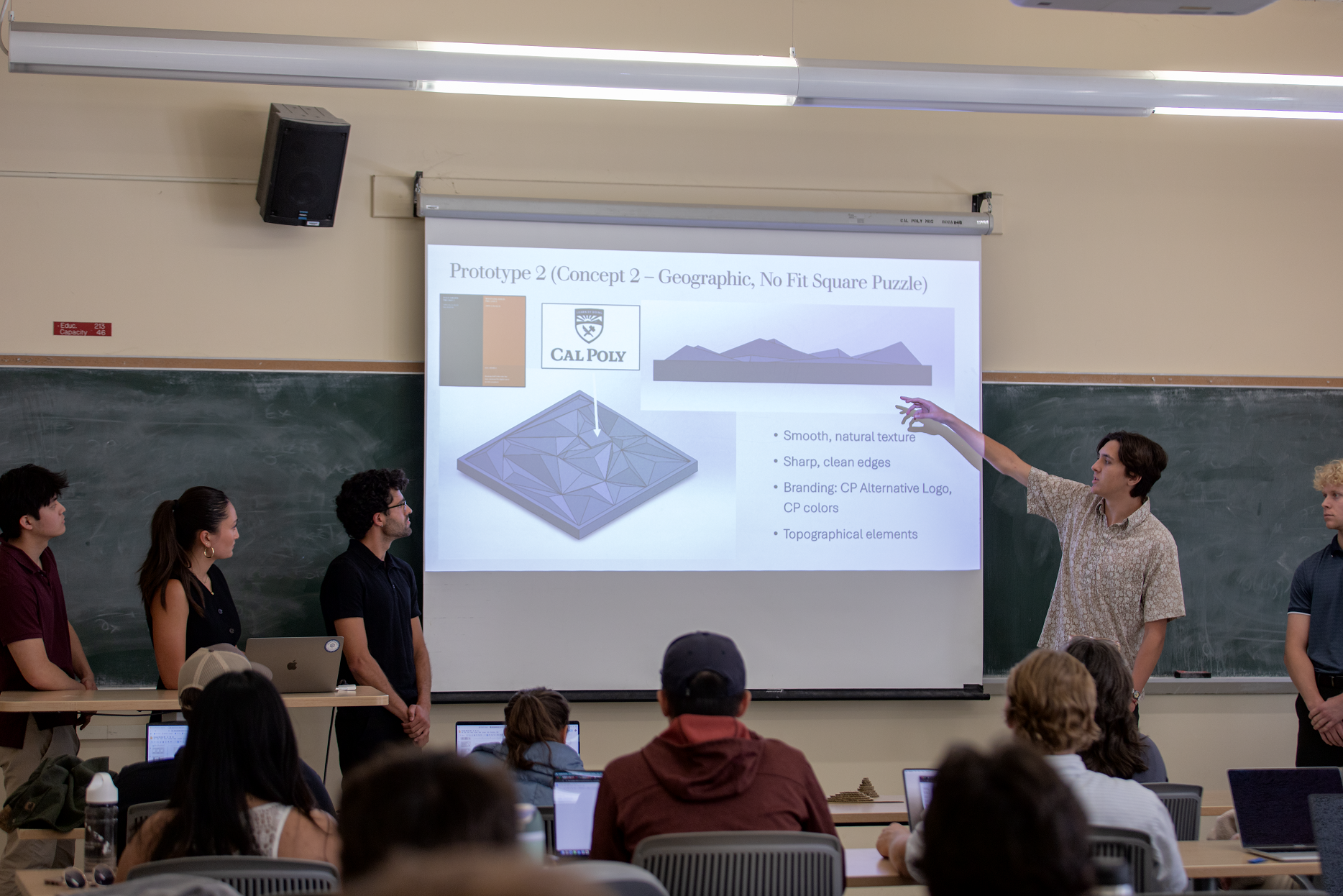 A students points to a PowerPoint slide during a presentation
