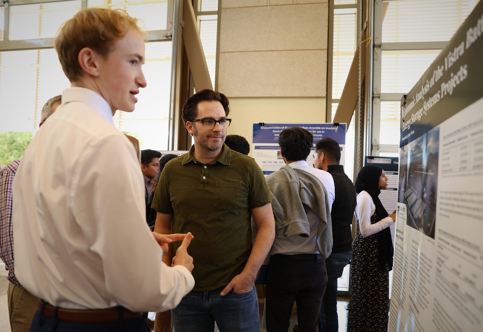 A professor listens to a student during a SURP Symposium 